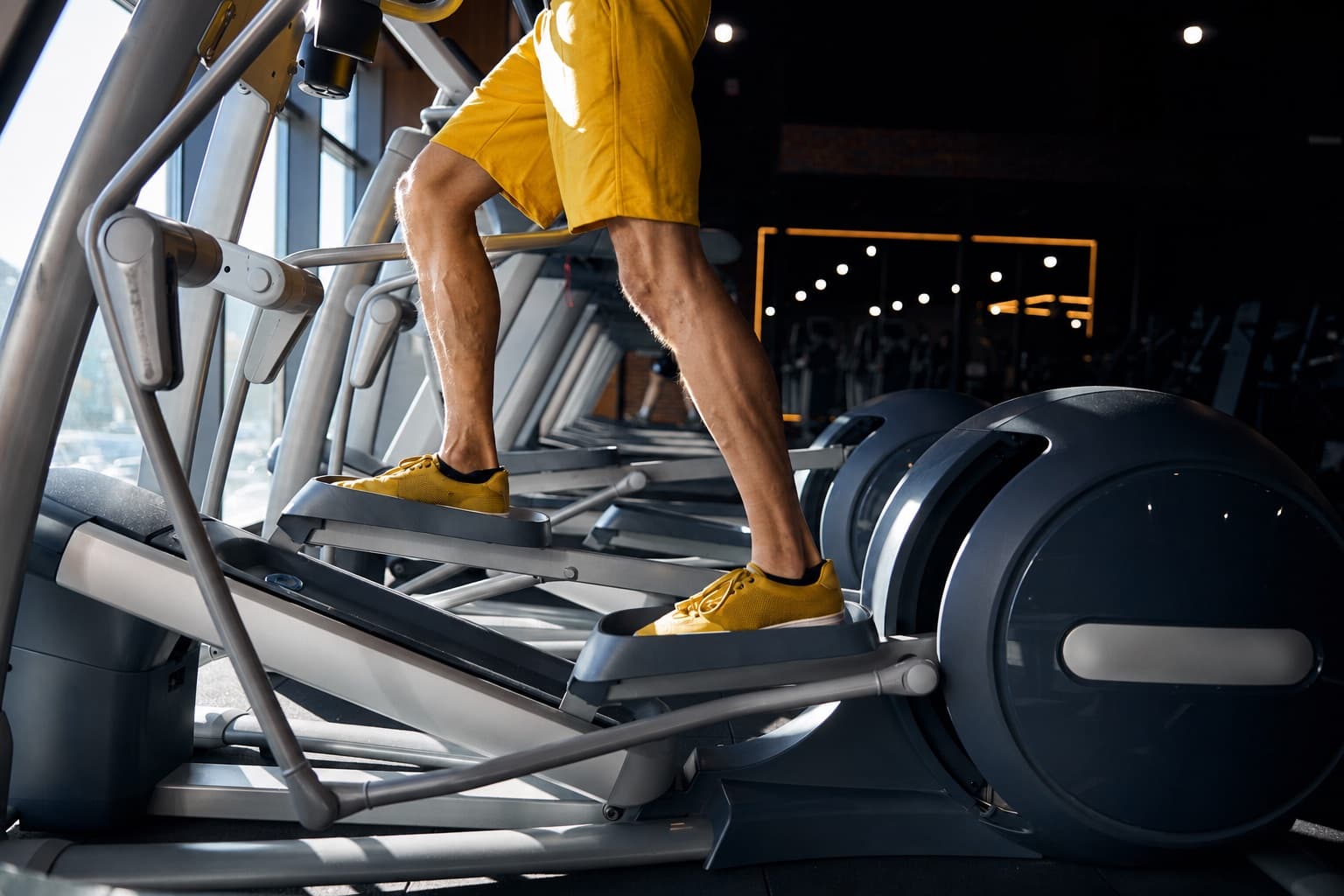 A member training on an elliptical machine in a modern gym